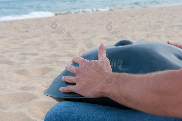 街头艺人坐在沙滩上玩绞盘