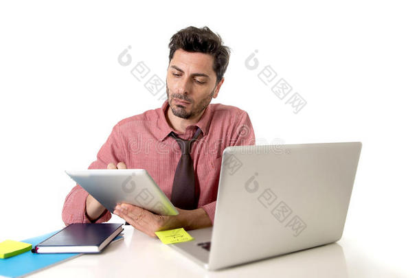 商人在办公桌上工作，使用数字平板<strong>电脑</strong>垫<strong>坐在电脑</strong>笔记本<strong>电脑前</strong>，看上去很忙