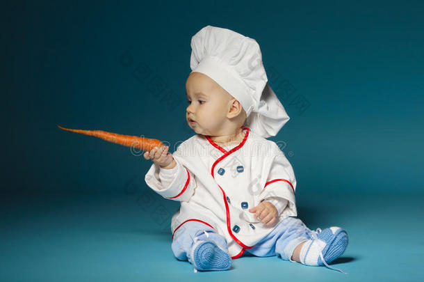 有趣的宝宝穿着烹饪服装拿着胡萝卜