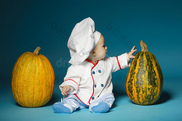 有趣的宝宝穿着烹饪服装拿着南瓜