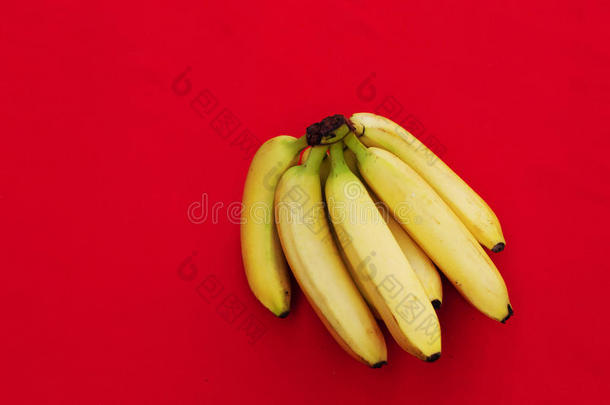 红色背景上的一堆<strong>香蕉</strong>。 新鲜有机<strong>香蕉</strong>，厨房桌子上的新鲜<strong>香蕉</strong>