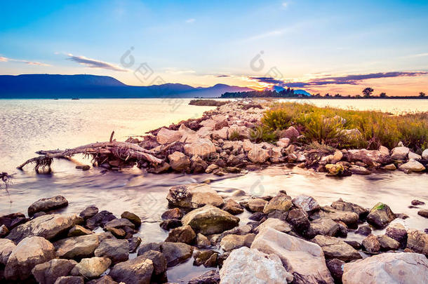 美丽的夏天日落在海边的岩石海岸上