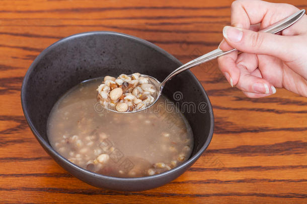手拿汤勺，把豆子汤放在碗上