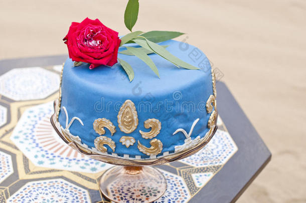 桌子上的<strong>蓝色婚礼</strong>蛋糕和上面的红玫瑰