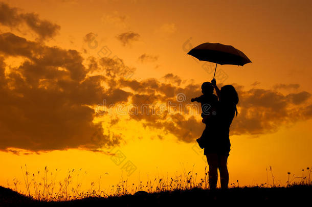 一对母子撑着雨伞，在日落时分在户外玩耍