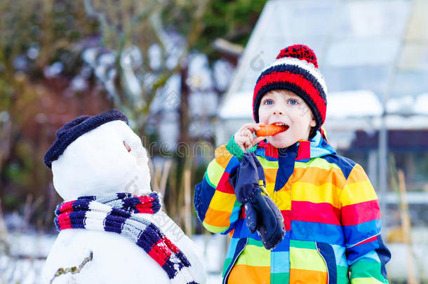 有趣的男孩穿着五颜六色的衣服堆雪人