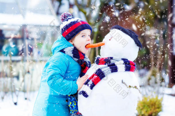 有趣的男孩穿着五颜六色的衣服堆雪人