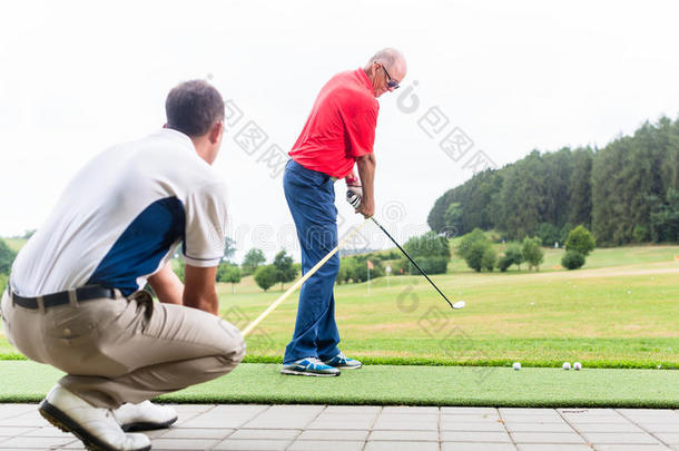 高尔夫教练与高尔夫球员在练习场工作