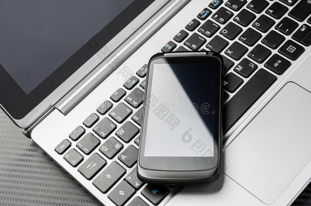 空白的黑色<strong>商务</strong>智能手机，反射躺在<strong>笔记本</strong>键盘上，都在碳层之上