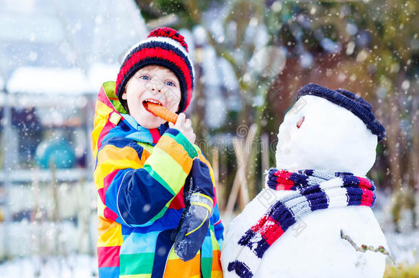 有趣的男孩穿着五颜六色的衣服堆雪人