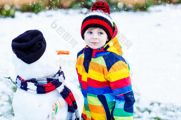有趣的男孩穿着五颜六色的衣服堆雪人