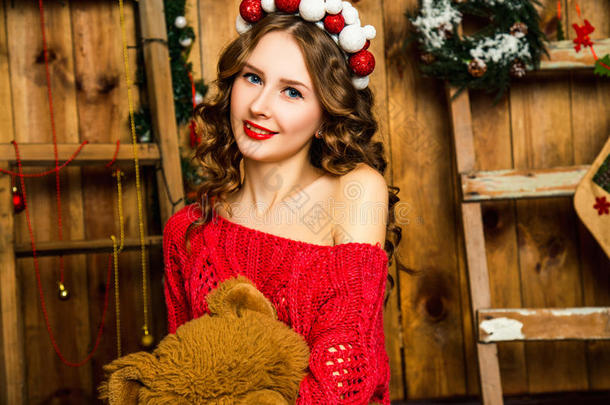 穿着红色毛衣的女孩坐着泰迪熊。 圣诞节和新的