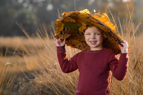 秋天树叶之间戴着帽子的孩子