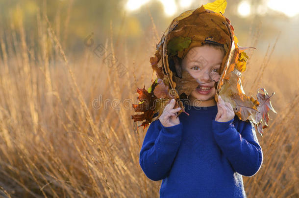 秋天树叶之间戴着帽子的孩子