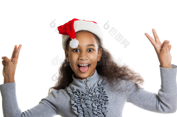 开朗的深色皮肤的女孩戴着红领巾和圣诞老人的帽子。