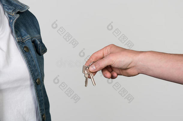 公寓钥匙移交给一个女人，隔离在灰色上。