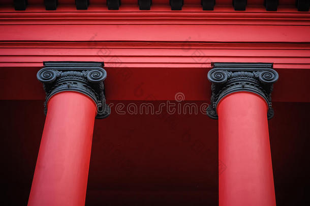 两根漂亮的红色柱子支撑旧红色建筑屋顶的细节