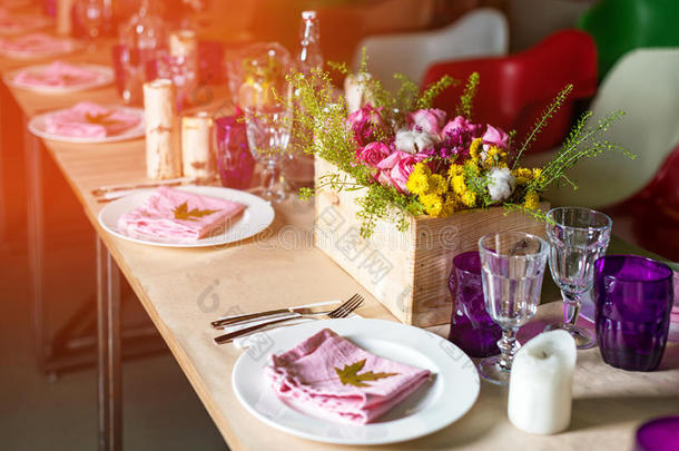装饰好的桌子准备晚餐。 装饰精美的桌子，配有鲜花、蜡烛、盘子和餐具，用于婚礼或婚礼