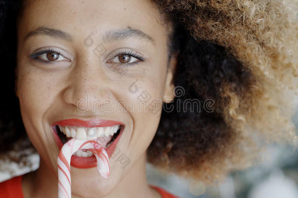 有趣的年轻女人咬圣诞糖果拐杖