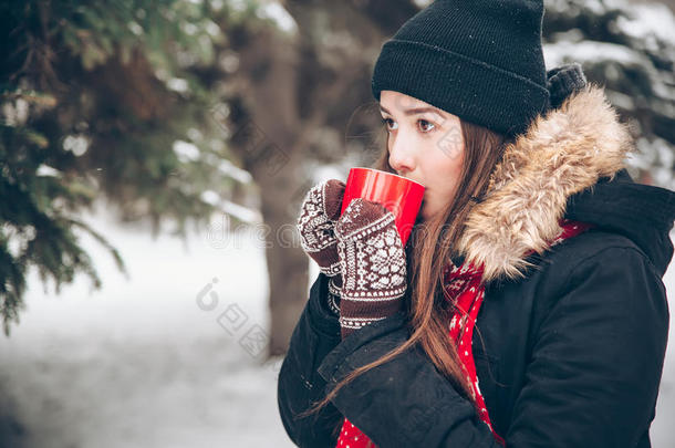 女孩在冬天的森林里喝热茶