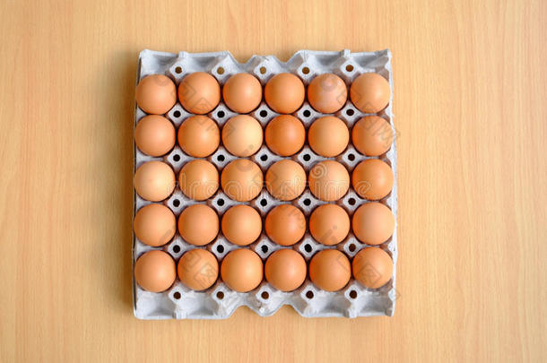 <strong>一打</strong>棕色的鸡蛋放在木桌上的纸箱里