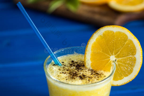 美味的橙汁在玻璃和橙色旁边的蓝色背景