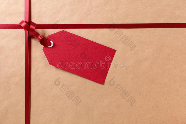 礼品标签和红色丝带，棕色包裹包装纸背景，复制空间