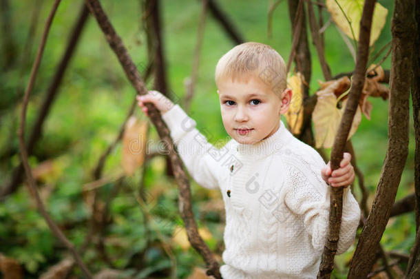 森林里穿着鲜艳毛衣的小男孩和藤蔓植物在一起