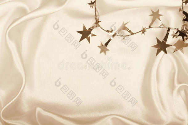 金色的星星和在丝绸上旋转作为背景。 在塞皮亚色调。
