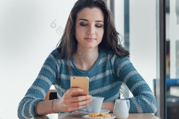 自信的年轻女人在咖啡馆使用智能<strong>手机</strong>