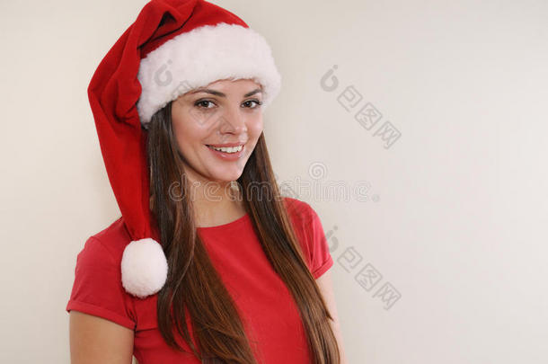 美丽的女人带着可爱的微笑，戴着圣诞老人的帽子，为圣诞节高兴