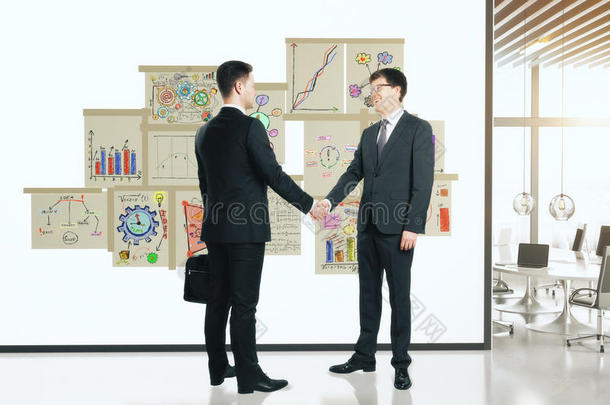 商业伙伴在白色墙上握手，海报上有BU