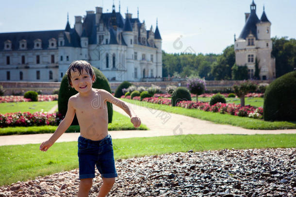 可爱的小男孩，在雨中在法国的一座城堡前玩耍