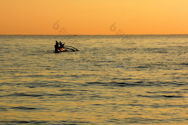 金色的热带日落，地平线上渔民的剪影。