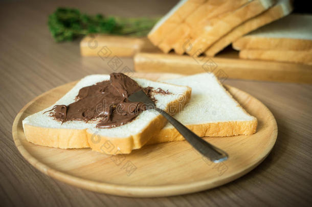 巧克力涂在木板上的面包片上。把注意力集中在涂有巧克力的面包上。