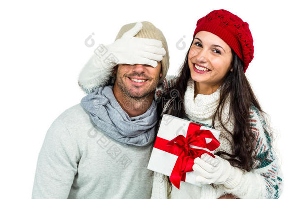微笑的女人遮住伴侣的眼睛，拿着礼物