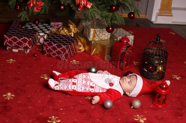 可爱的小圣诞老人<strong>宝宝</strong>睡在圣诞树旁边，带着很多<strong>礼</strong>物