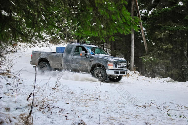 在森林的冬季雪路上漂流的4x4卡车