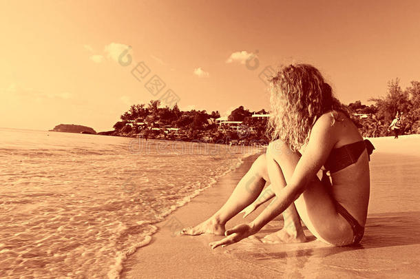 美丽的卷发女孩在海滩上休息