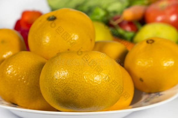 特写橙色橘子成一道菜，前面有几种蔬菜