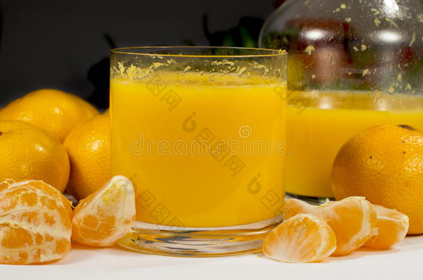 一杯橙汁在一个罐子和几个水果旁边
