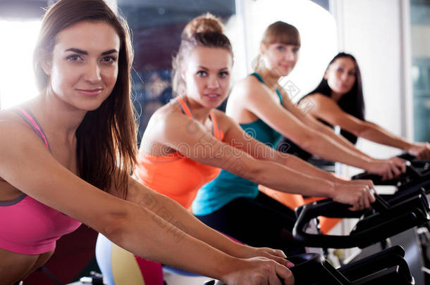一群四个女人在健身房骑自行车