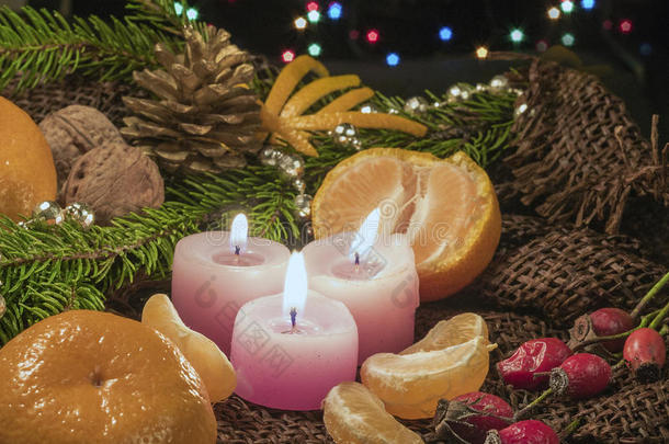 圣诞蜡烛和装饰品，橘子和坚果在黑暗的背景上，灯芯和装饰品在黑暗的巴克斯