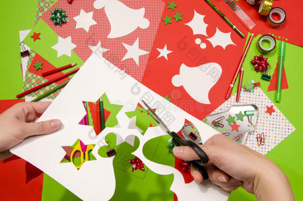 一个女人的手切一个白色<strong>纸板</strong>与圣诞节的<strong>形状</strong>，星星和铃铛。