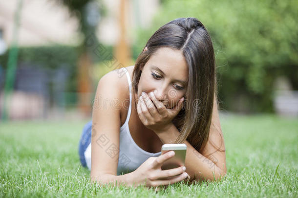 迷人的十几岁的女孩在草地上躺着的时候收到了一<strong>条令</strong>人惊讶的短信