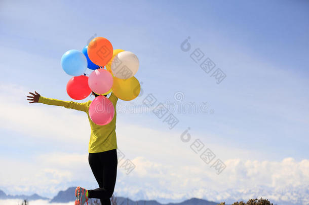 欢呼的年轻女子张开双臂，<strong>拿</strong>着<strong>气球</strong>
