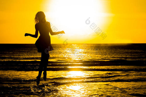 无忧无虑的女人在海滩上的日落中跳舞。 假期维塔
