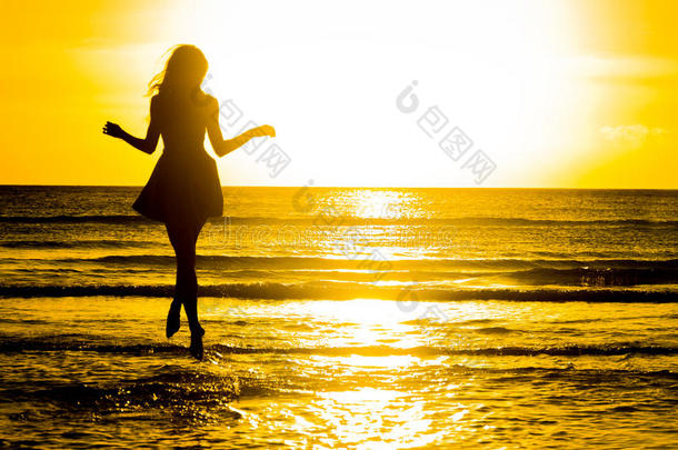 无忧无虑的女人在海滩上的日落中跳舞。 假期维塔