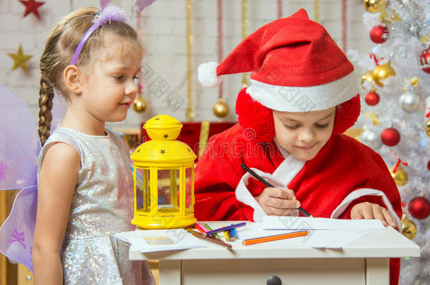 打扮成圣诞老人的女孩用一封信在信封上签名，站在一个打扮成仙女的女孩旁边