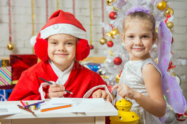 女孩穿着圣诞老人的衣服写着<strong>一封信</strong>，站在仙女旁边，手里拿着手电筒